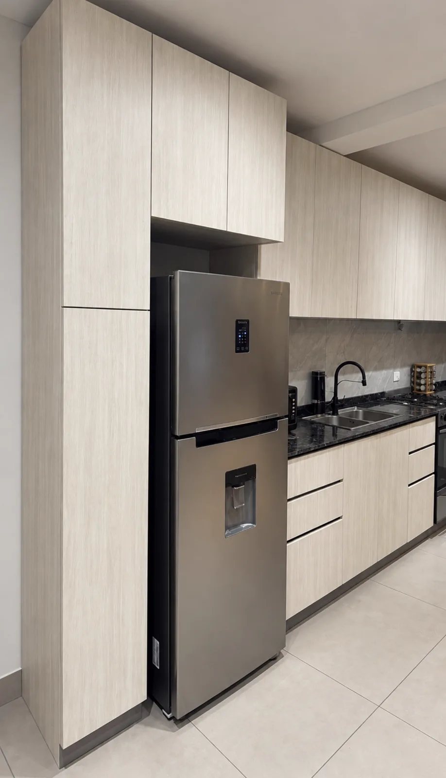 Cocina en tonos claros con heladera integrada y mesada oscura