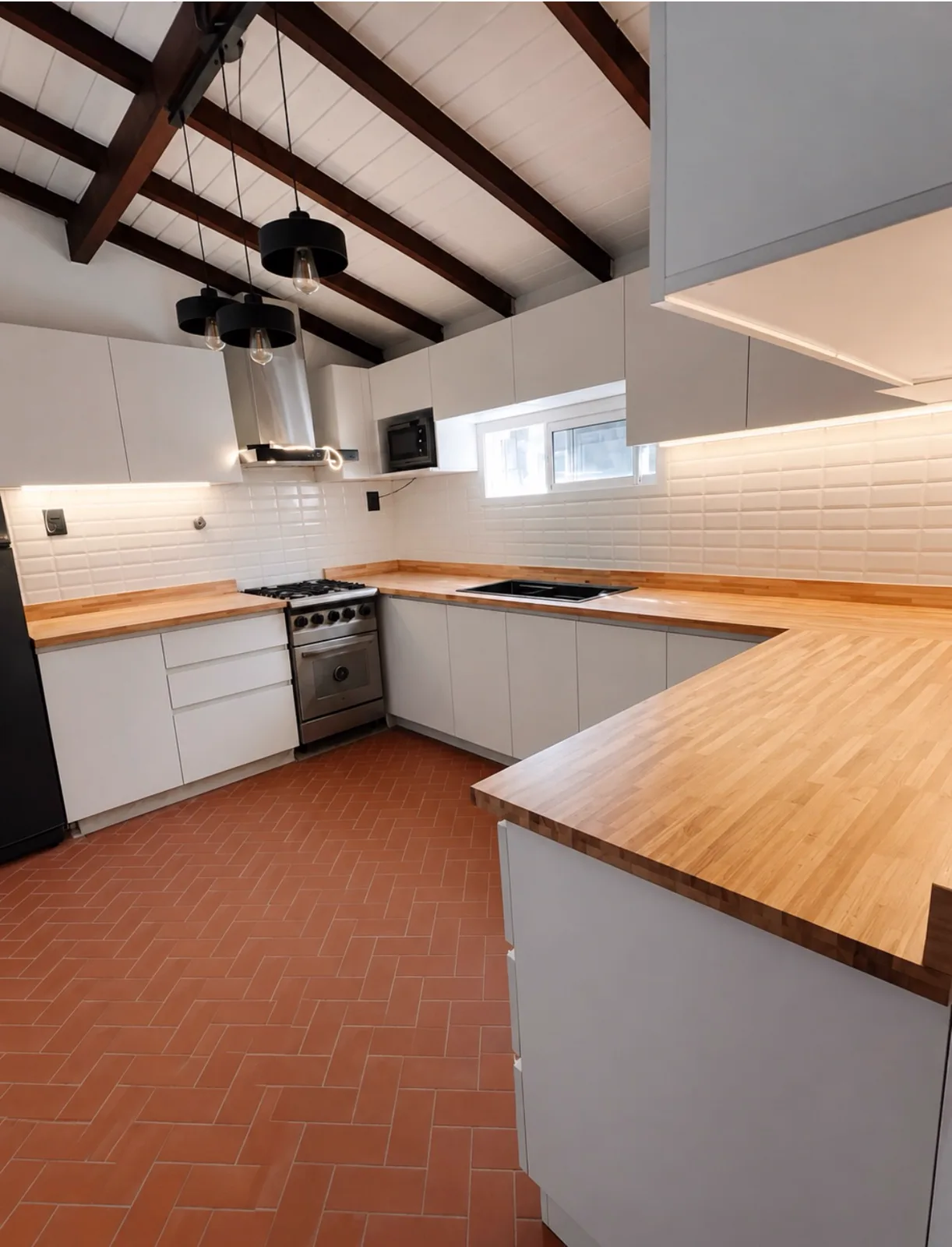 Cocina blanca con mesada de madera, lavarropas integrado y piso terracota