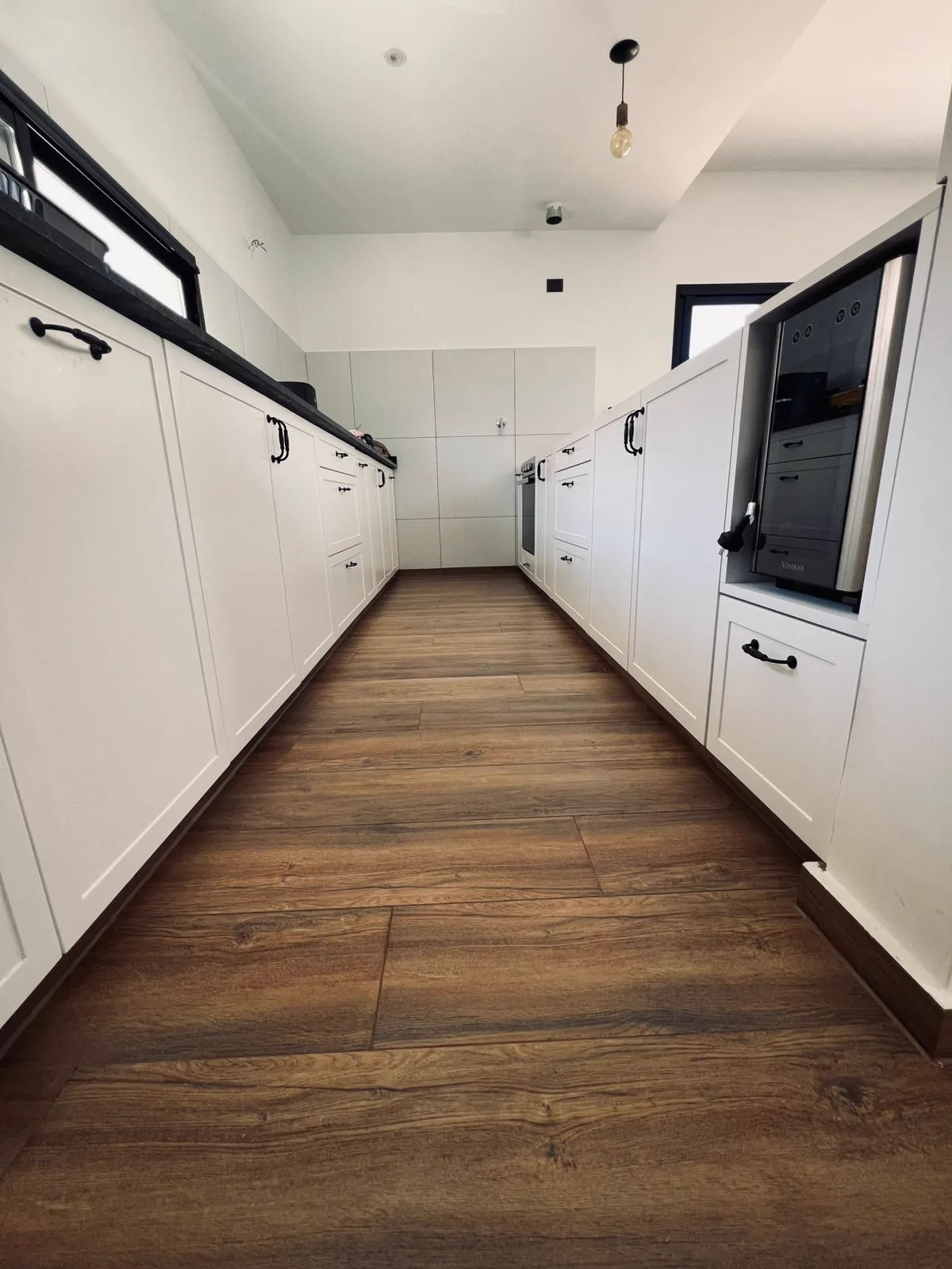 Cocina laqueada con herrajes negros y piso de madera